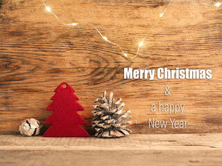 Red felt tree shape with pine cones on a wooden background, Merry Christmas and a happy New Year