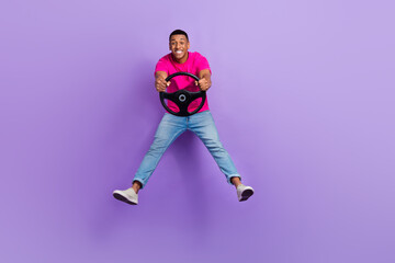 Fototapeta na wymiar Full body photo of excited cheerful person jumping hands hold wheel isolated on violet color background