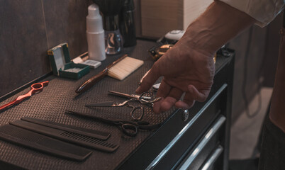 Detalle de mano de peluquero cogiendo el material de trabajo, en la peluquería. - obrazy, fototapety, plakaty