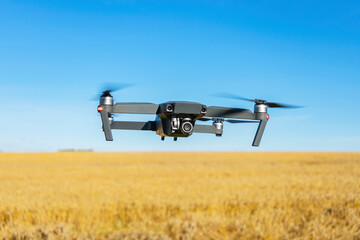 Drone quadcopter with a camera hovered over a wheat field