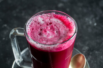 Beetroot vanilla latte from fresh beetroot juice blended with vanilla and milk in a transparent cup on the table in cafe, closeup. Trendy healthy drink