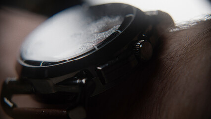 Extreme close-up of blurry looking wristwatch with water particles, wearing on the arm, background...