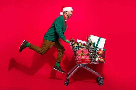 Full length photo of funky cool man wear x-mas green cardigan running buying noel presents bargains isolated red color background