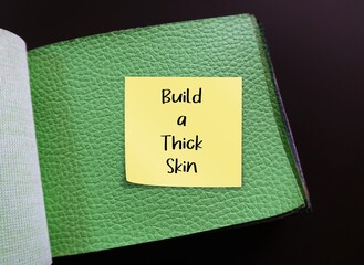 Green articicial PU leather sample with stick note written BUILD A THICK SKIN, self reminder to...