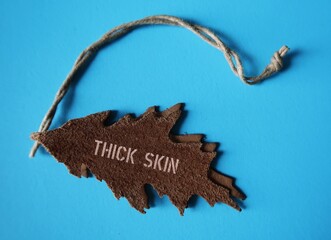Leather tag with text THICK SKIN, concept of highly sensitive people learn to be less sensitive and...