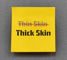 Yellow note with text THIN SKIN (chnage to) THICK SKIN, concept of highly sensitive people learn to be less sensitive and develop thick skin to handle criticism and stop take things personally