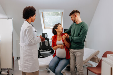 Cheerful pregnant woman at doctors with husband.