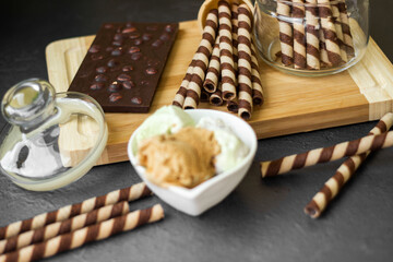Sweet table with chocolate waffles, chocolate and ice cream on a black background. Waffle rolls