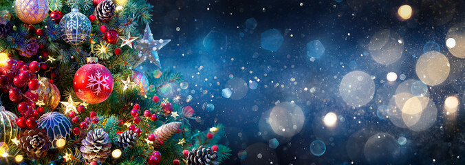 Weihnachtsbaum mit Kugeln in blauer Nacht - Ornamente auf Tannenzweigen mit glitzernden und defokussierten Lichtern im abstrakten Hintergrund