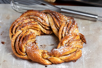 Roscón de reyes Kringle Estonia. Typical Christmas sweet, braided sponge cake with cinnamon, butter, walnuts or almonds and icing sugar on a white background.