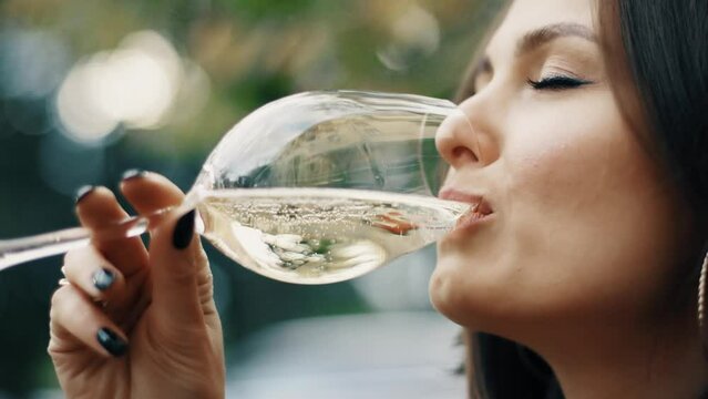 Beautiful brunette woman sitting on outdoor terrace. Caucasian female drinking champagne in the restautant. Slylish lady in bistro.