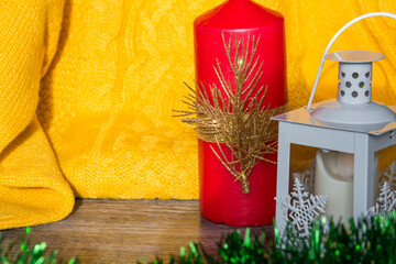 Christmas decorations and decorations with a yellow sweater and a red candle on a wooden surface.