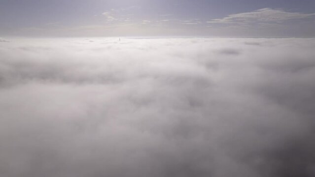 Aerial time lapse shot of the top of Ulm minster sticking through a moving and wafting sea of clouds on a morning in autumn