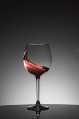 Red colors and smooth, sinuous movement of red wine inside a glass. Backlight studio shot.