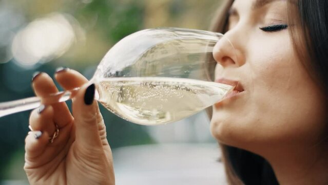 Beautiful brunette woman sitting on outdoor terrace. Caucasian female drinking champagne in the restautant. Slylish lady in bistro.
