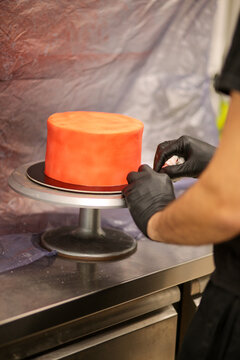 pastry chef designer using edible red paint airbrush to spray frosted cup cake