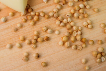 Coriander seeds scattered on a wooden cutting board. Seasoning with a distinctive herbal aroma