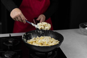 Chef cook making mac and cheese with white cream sauce. Pasta macaroni and liquid yellow cheese. Ingredients: macaroni, milk, cheese, flour, butter.
