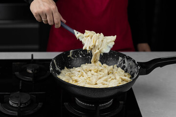 Chef cook making mac and cheese with white cream sauce. Pasta macaroni and liquid yellow cheese. Ingredients: macaroni, milk, cheese, flour, butter.