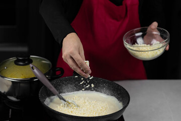 Chef cook making white cheese sauce for mac and cheese meal. Ingredients: Milk, cheese, flour and...