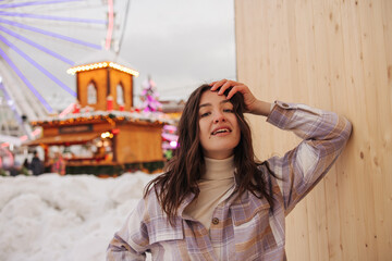 Close-up of young caucasian girl relaxing looking at camera spends time in amusement park. Brunette wears golf and shirt. Lifestyle, stylish vacation concept.