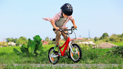 Young rider kid in helmet and sunglasses riding bicycle