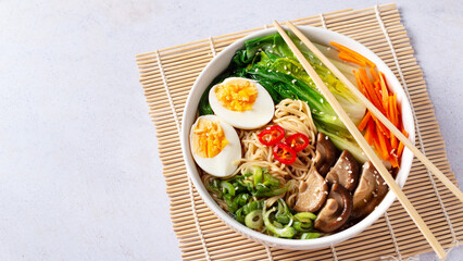 Ramen noodle soup with eggs, mushrooms, pak choi in white bowl