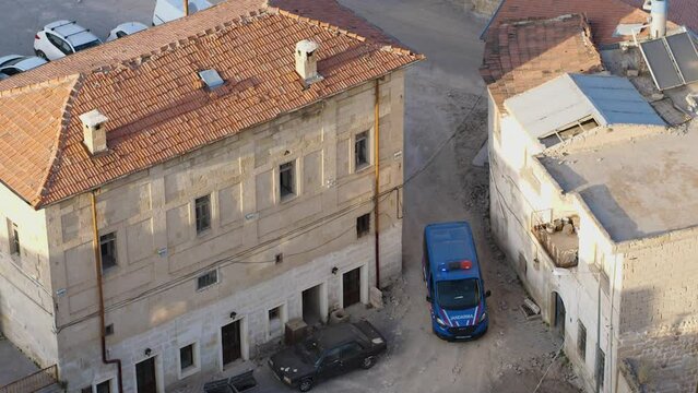 A gendarme patrol car with flashing beacons on stands in the old city quarter. Near the stone buildings with tiled roofs. Top view. Policing in Cappadocia, Turkey