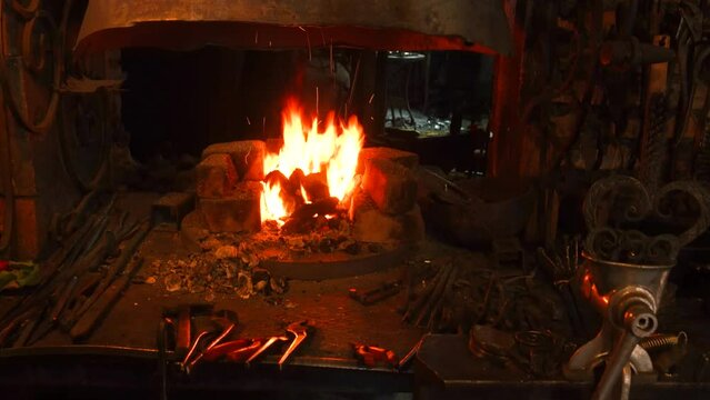 the flame of the blacksmith's hearth. blacksmith's workplace. blacksmith tools. blacksmith working with hot glowing metal, bending steel in a smithery. High quality 4k footage
