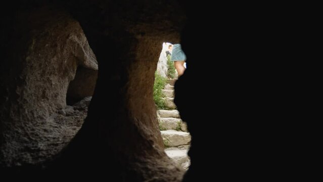 A girl tourist climbs the steps in a rock castle in Avanos, Nevshehir. A traveler with an action camera takes in the sights of Cappadocia. View from a cave