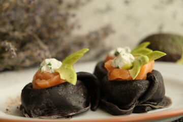 Festive bright appetizer. New Year's table. black pancakes with cuttlefish ink, salmon and avocado. black food. pancake week. Vegetarian pancakes. seafood. Useful lunch. homemade food