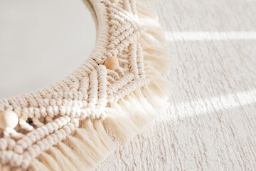 Macrame mirror on a white wall.  Eco-style. Natural materials. Soft fokus. Close up image.  Cotton rope decor macrame to make your room more cozy and unique.