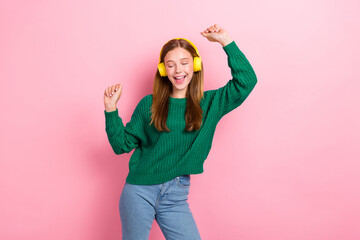 Photo portrait of cute little girl listen music earphones dancing dressed stylish green knitted garment isolated on pink color background