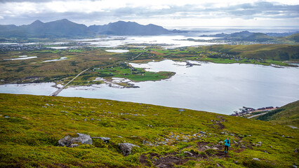 Fototapeta premium girl with backpack hiking Offersøykammen trail head admiring the panorama of lofoten islands, Norway; hiking in the Norwegian fjords