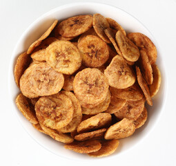Fried banana chips in a white bowl on a white background