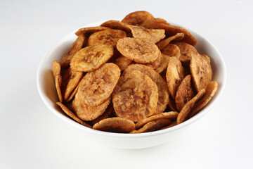 Fried banana chips in a white bowl on a white background