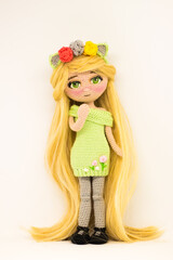 Knitted interior amigurumi doll with yellow hair in green dress. Handmade concept.