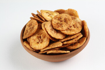 Fried banana chips in a terracotta bowl on a white background