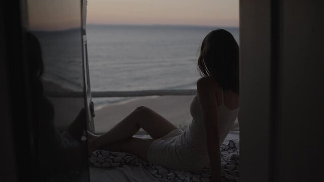 Woman sitting in the back of the camper van motor home watching romantic sunset