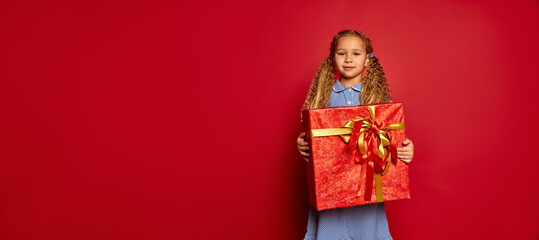 Fototapeta premium Great gift. Happy smiling little girl, child in casual outfit with box in festive package at holiday. Merry Christmas, New Year. Concept of emotions, dreams, birthday, happy childhood, wishes