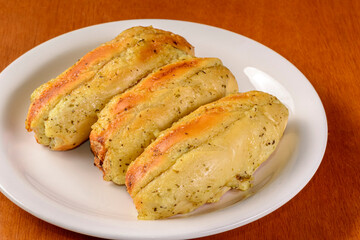 Three garlic breads in white plate on wooden table. Brazilian garlic bread.