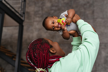 Young african american woman playing with her baby son at home