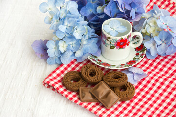 cup with flowers and chocolate biscuits on top of a table