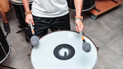 Hands of an unrecognizable person playing a drum with maces