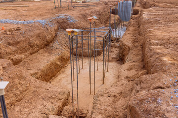 Reinforcement with steel bars rebar wires is put into trench for concrete foundation at construction site