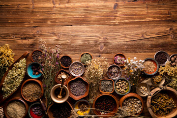 Natural medicine background. Assorted dry herbs in bowls, mortar and plants on rustic wooden table. - obrazy, fototapety, plakaty