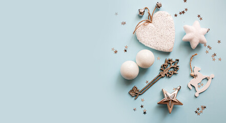 Christmas or New Year's flat lay composition of various decorative elements, sparkles and Christmas decorations in white and silver colors on a pastel light blue background. top view. copy space. 