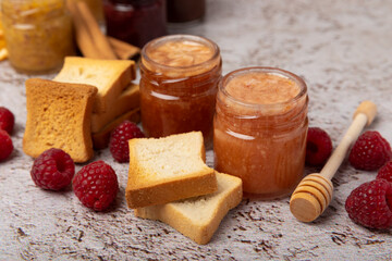 Toasted bread toast with jam. A jar of raspberry jam. Delicious toast with sweet jam served for breakfast on the table. Delicious toasts on a textured background. Space for text. Place for copying.