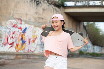 Teenager girl, Beautiful happy Asian healthy woman smiling, riding and playing extreme sports skateboard as outdoor activity with happiness, relaxation during holidays in summer vacation.