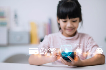 Child safety online. Little girl using smartphone at home. icon of internet blocking app on foreground